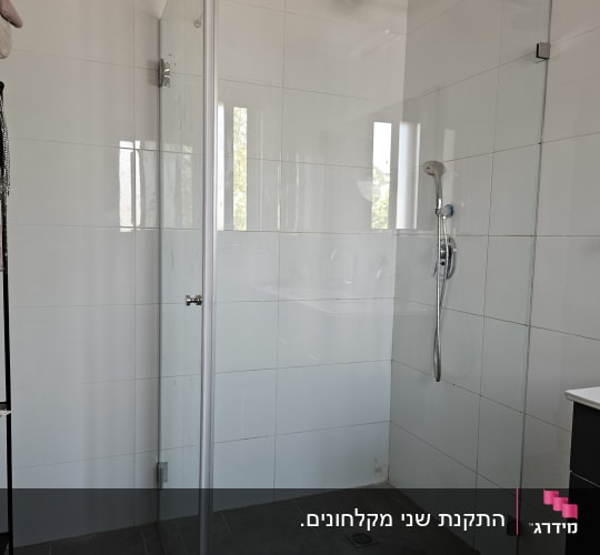 מקלחון זכוכית פינתי מותקן בחדר רחצה עם חיפוי אריחים לבנים